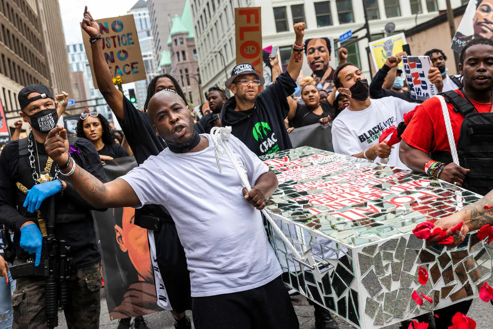 Protestors at a demonstration following the murder of George Floyd carry a mock casket covered in mirror shards