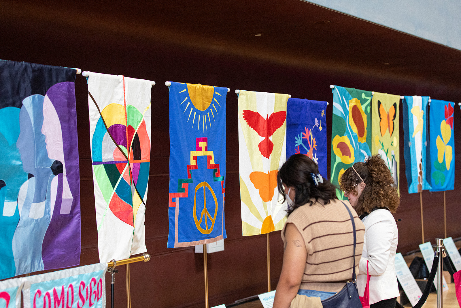 Two people gaze at colorful textile banners