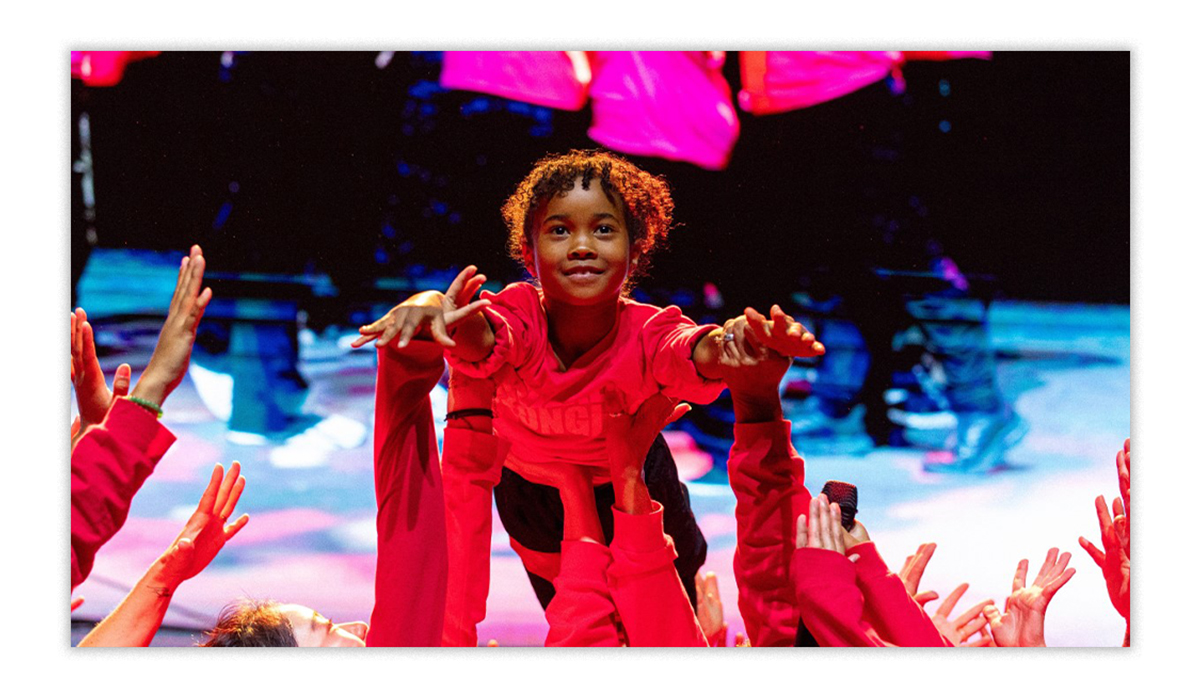 A young person is supported in the air by a group of people