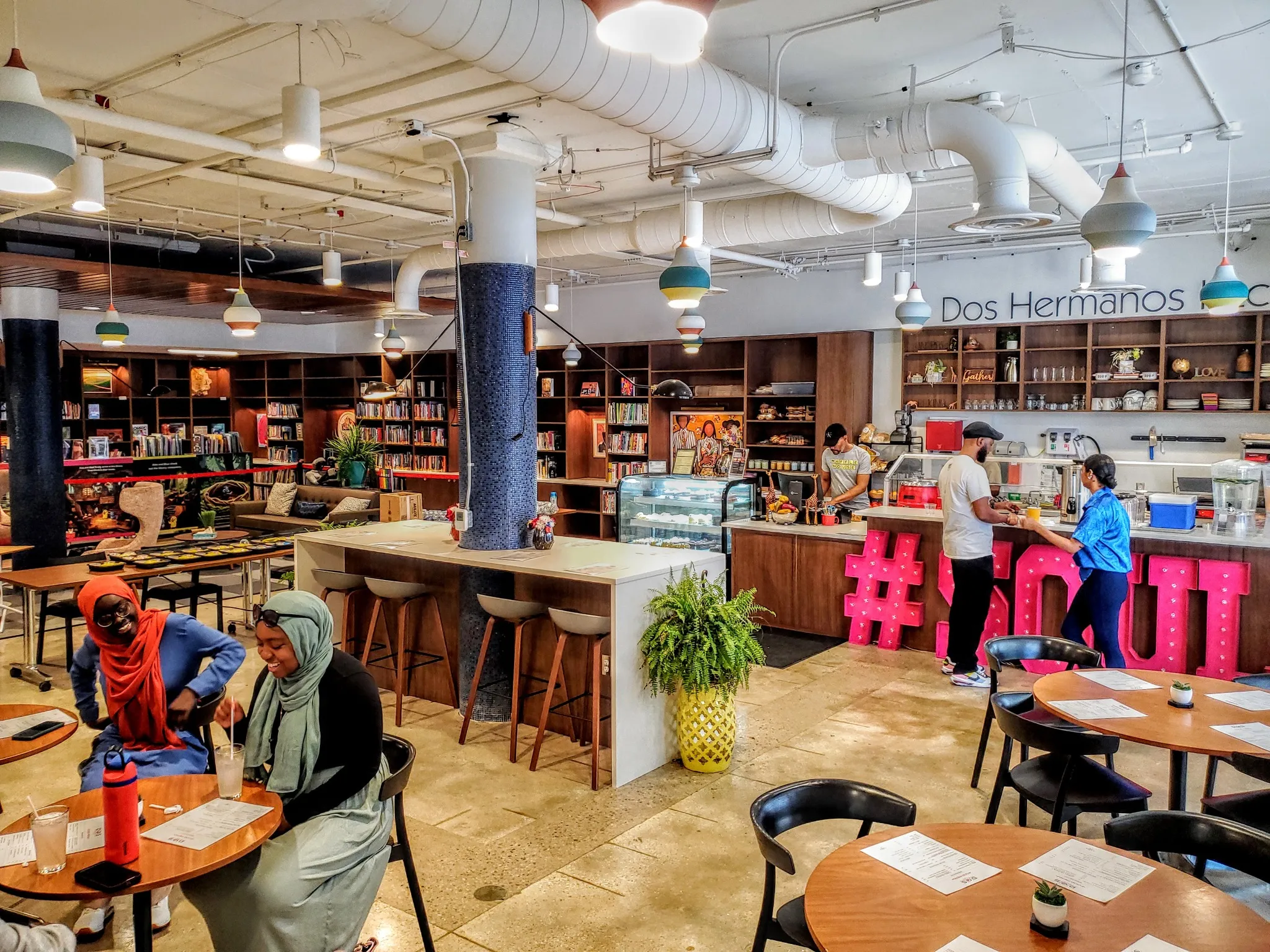 People conversing in a colorful cafe built within a library.