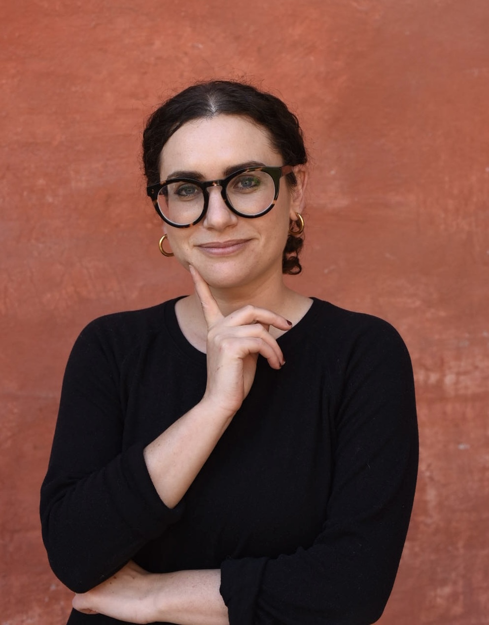 Headshot of Sara Grossman, dark hair with large black glasses and black shirt