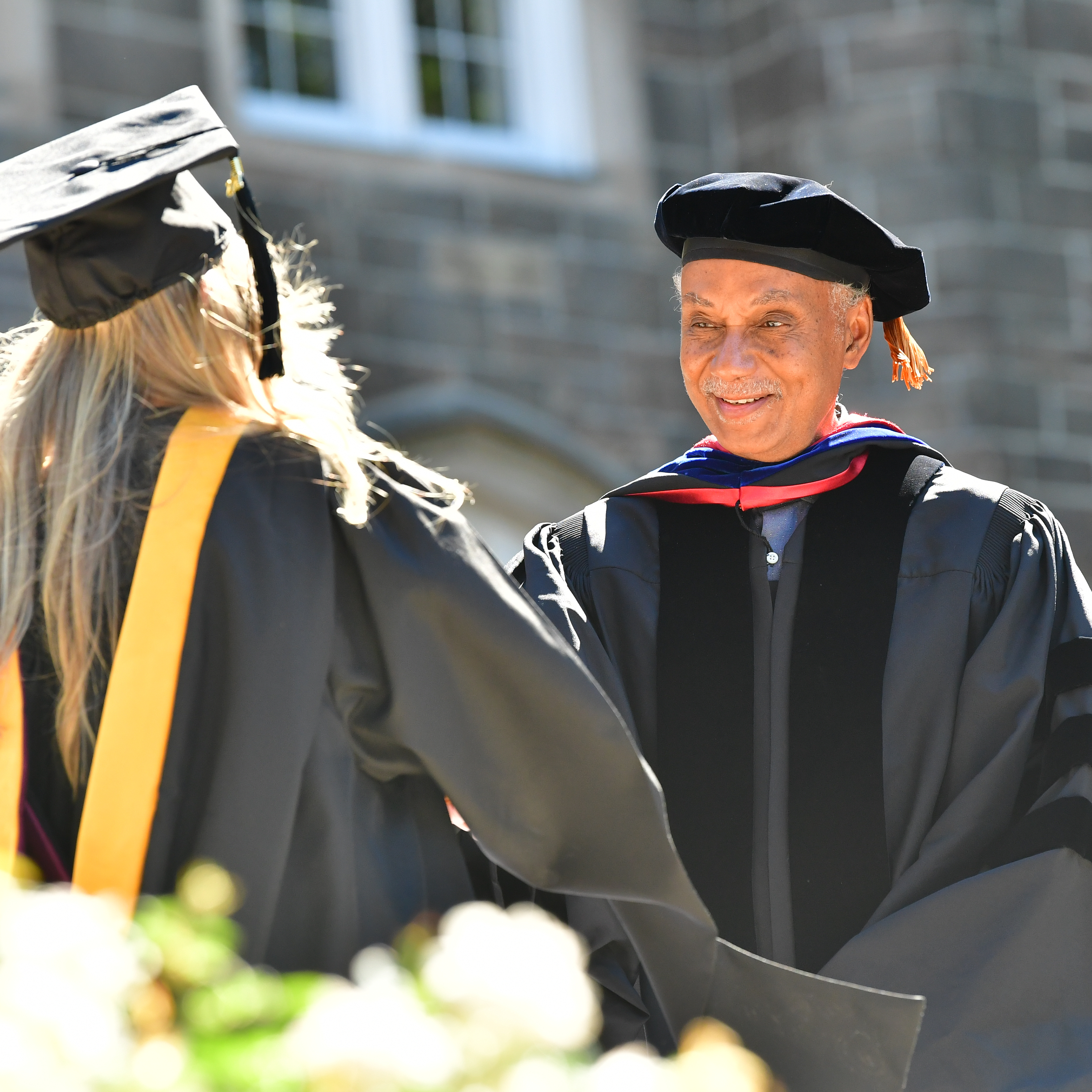 Tyler Stovall shaking hands with a graduating student at a commencement ceremony