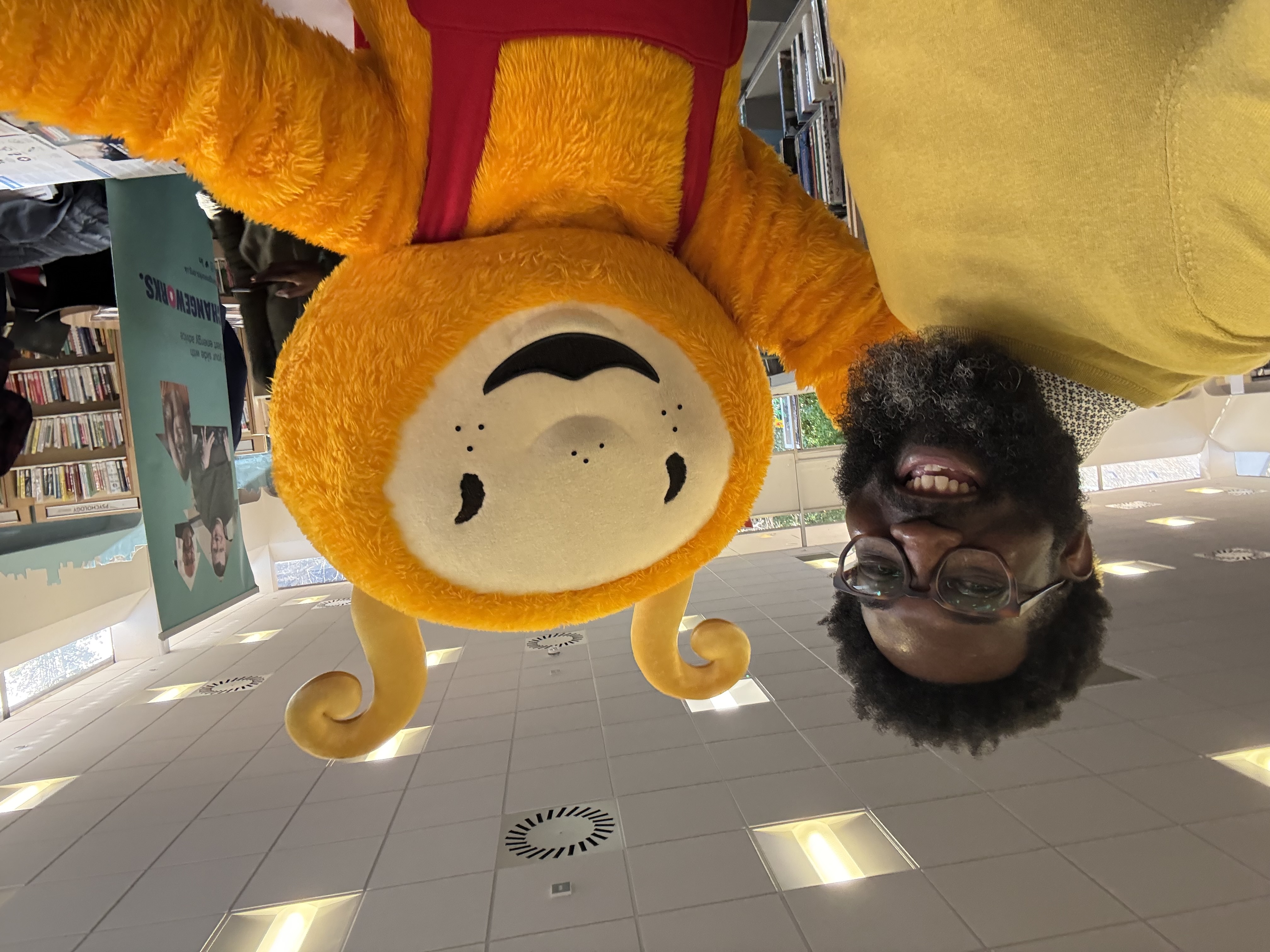 Shamichael Hallman posing with a person dressed as a bee inside of a library.