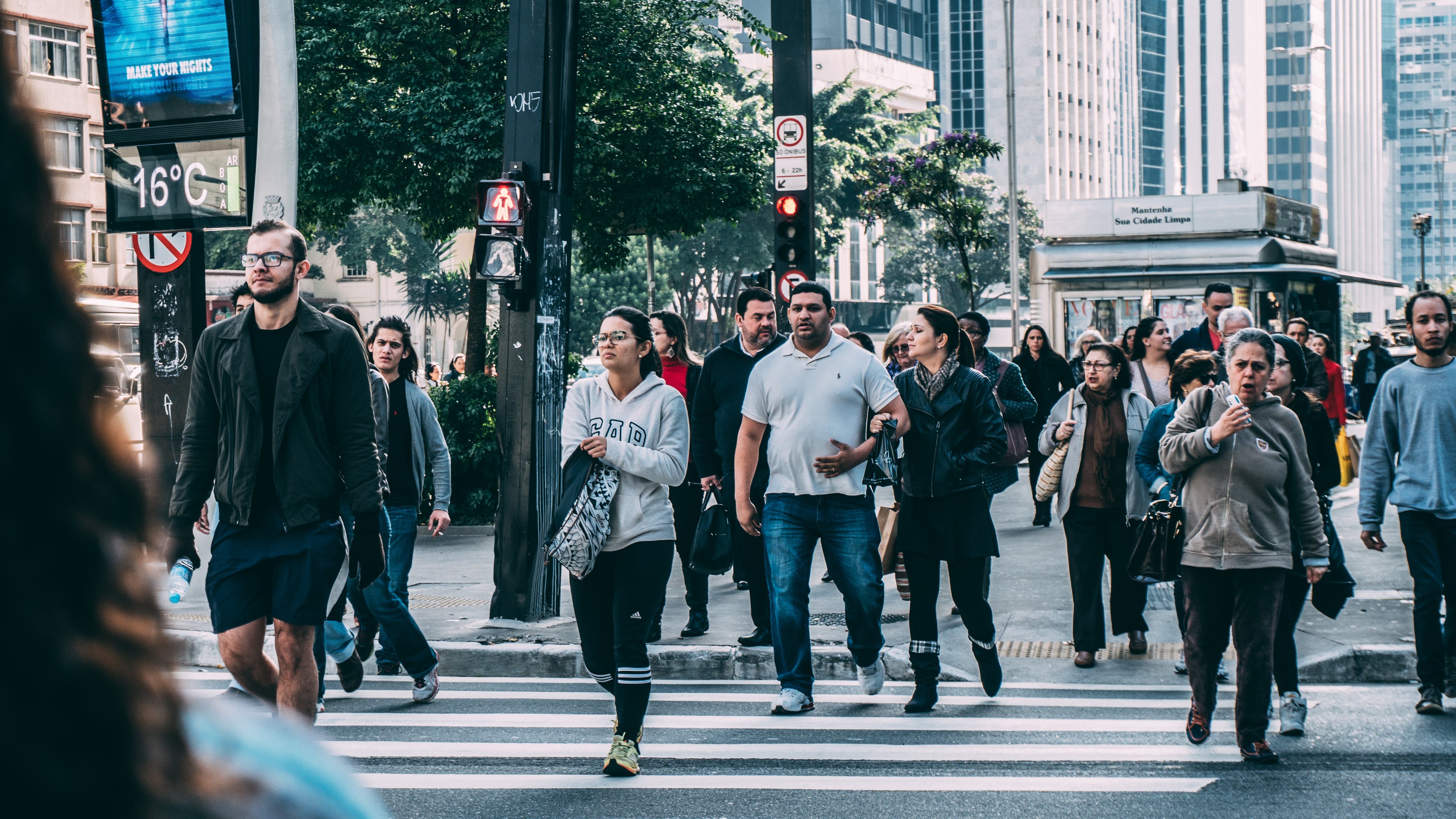 Pedestrians cross the street at a busy crosswalk.