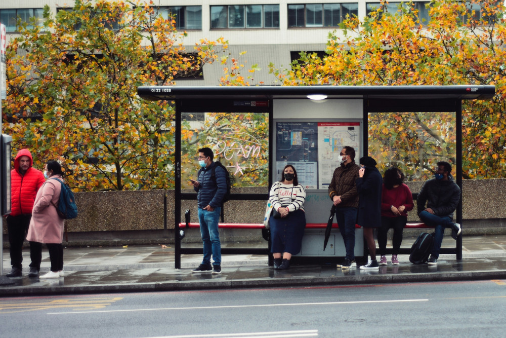 People wait at a bus stop in London. (Photo by Sandy Ravaloniaina / Unsplash)