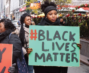 This image is of a protestor holding a sign that reads "#blacklivesmatter" 